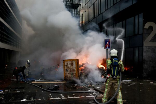 Бельгийские пожарные тушат пожара во время демонстрации против мер борьбы с Covid-19 в Брюсселе. - Sputnik Азербайджан