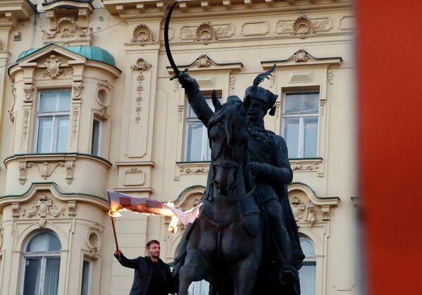 Мужчина сжигает флаг во время акции протеста против вакцинации и мер против коронавируса в Загребе, Хорватия. - Sputnik Азербайджан