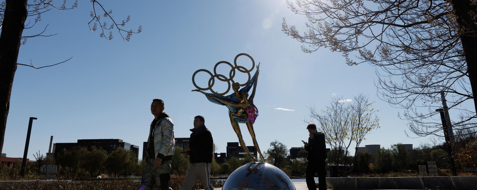Люди проходя мимо скульптуры в виде олимпийских колец в Пекине - Sputnik Азербайджан, 1920, 23.11.2021