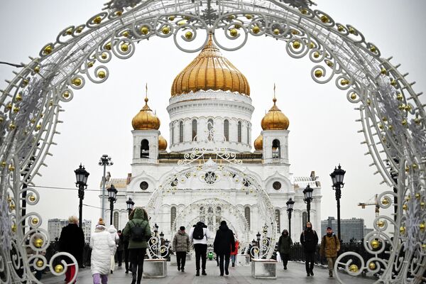Пешеходы проходят через рождественские украшения перед Храмом Христа Спасителя, главным русским православным храмом, в Москве. - Sputnik Азербайджан