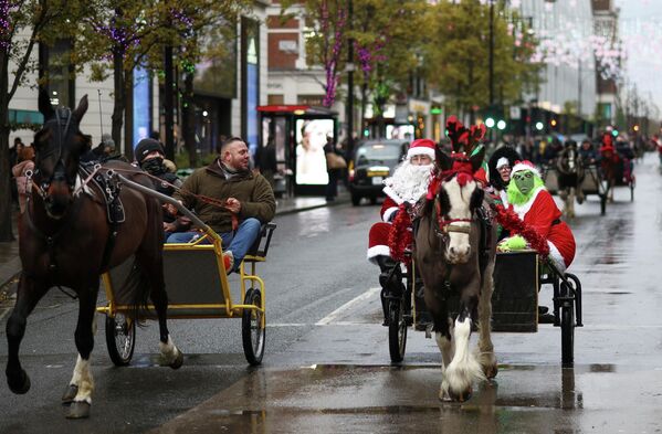 Люди в рождественских нарядах едут в запряженной лошадьми повозке в Лондоне, Великобритания. - Sputnik Азербайджан