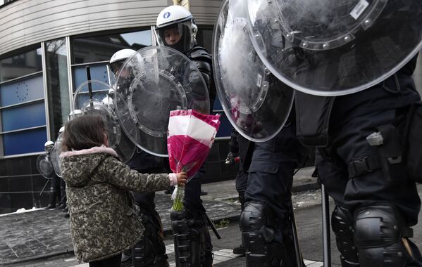 Девочка дарит цветы сотрудникам ОМОНа во время акции протеста против мер по борьбе с коронавирусом в Брюсселе, Бельгия. - Sputnik Азербайджан