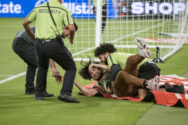 Охрана ловит фаната, выбежавшего на поле после международного товарищеского матча между Мексикой и Чили. - Sputnik Азербайджан