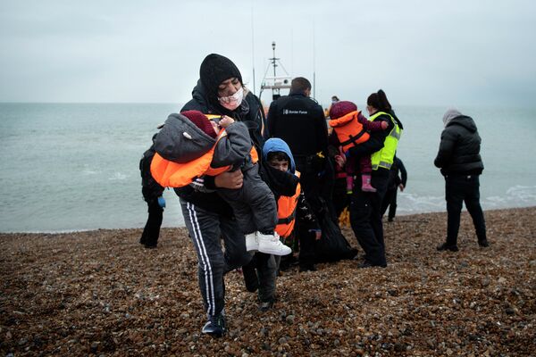 Женщина-мигрант несет своих детей после того, как ее спасли при пересечении Ла-Манша. - Sputnik Азербайджан