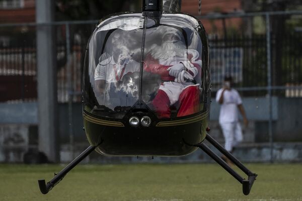 Мужчина в костюме Санта-Клауса прибывает на вертолете на празднование Рождества в Рио-де-Жанейро, Бразилия. - Sputnik Азербайджан