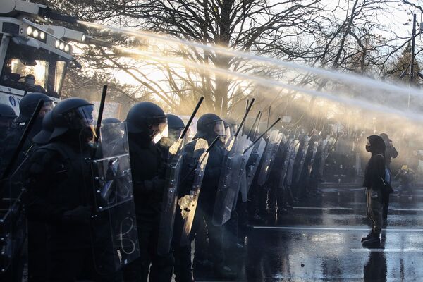 Противники вакцинации напротив полицейских, применяющих водомёты во время демонстрации против мер правительства по сдерживанию распространения Covid-19 в Люксембурге. - Sputnik Азербайджан