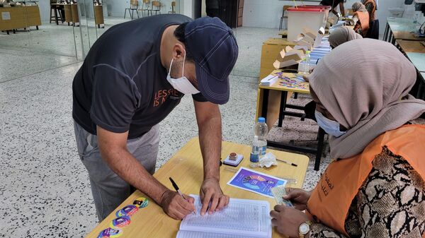 Мужчина из Ливии регистрируется для голосования на избирательном участке в Триполи - Sputnik Азербайджан