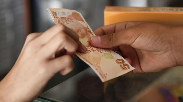 Покупатель платит продавцу банкнотой турецкой лиры, фото из архива - Sputnik Азербайджан
