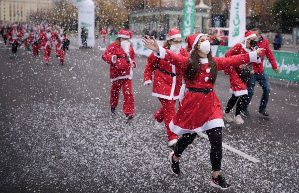 Люди в костюмах Санта-Клауса принимают участие в благотворительном забеге по сбору средств в помощь жертвам извержения вулкана Кумбре-Вьеха в Мадриде, Испания. - Sputnik Азербайджан