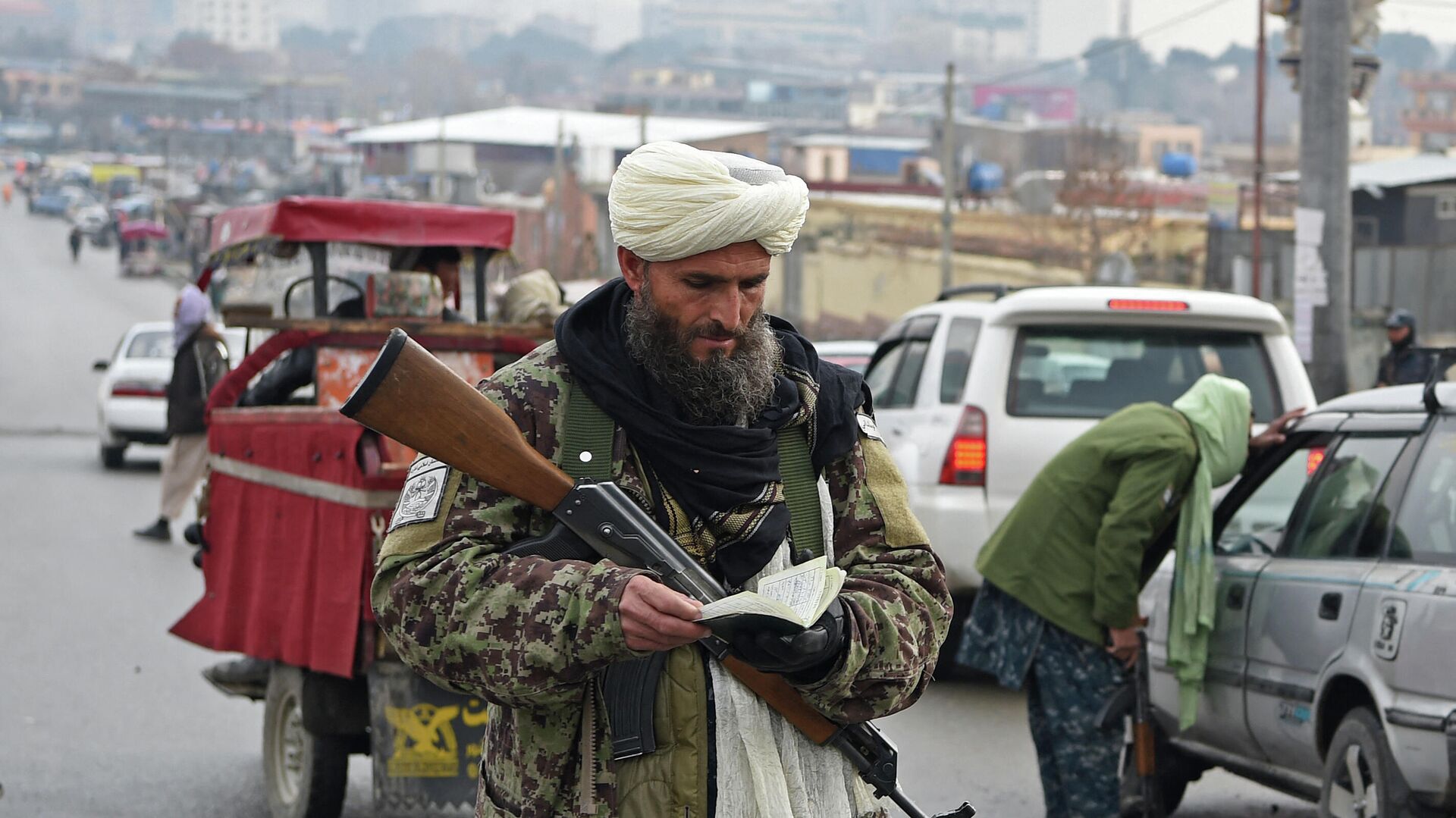 Член Талибана проверяет документ автомобилиста на блокпосту в Кабуле 23 декабря 2021 года. - Sputnik Azərbaycan, 1920, 03.01.2022