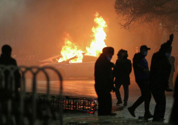 Etirazçılar yanan polis avtomobilinin yaxınlığında. - Sputnik Azərbaycan