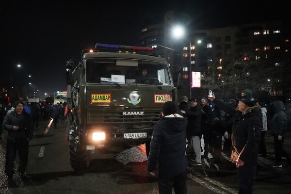Демонстранты пытаются заблокировать полицейский грузовик во время акции протеста в центре Алматы. - Sputnik Азербайджан