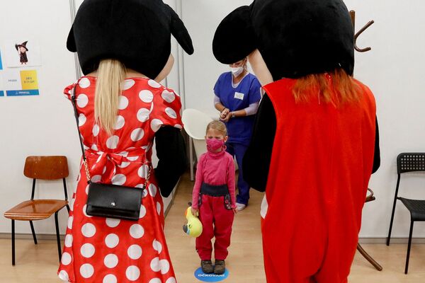 Медицинский персонал в костюмах развлекает ребенка, получившего прививку от коронавируса в центре массовой вакцинации в Праге, Чешская Республика. - Sputnik Азербайджан
