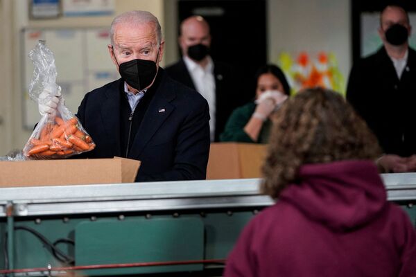 Президент США Джо Байден кладет пакет моркови в коробку организации по оказанию помощи голодающим в Филадельфии. - Sputnik Азербайджан