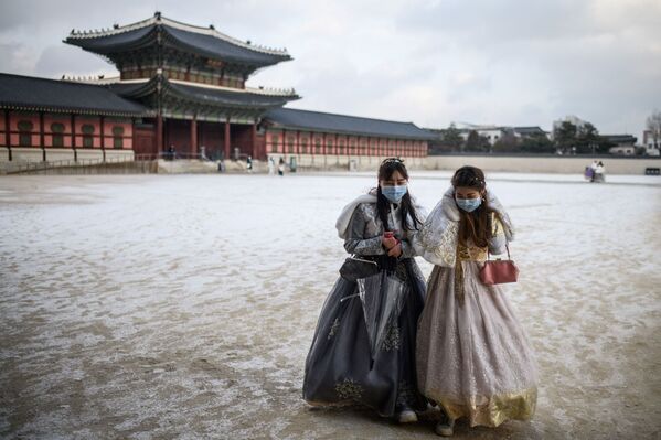 Посетительницы в традиционной одежде ханбок идут по территории дворца Кенбоккун после снегопада в Сеуле, Южная Корея. - Sputnik Азербайджан