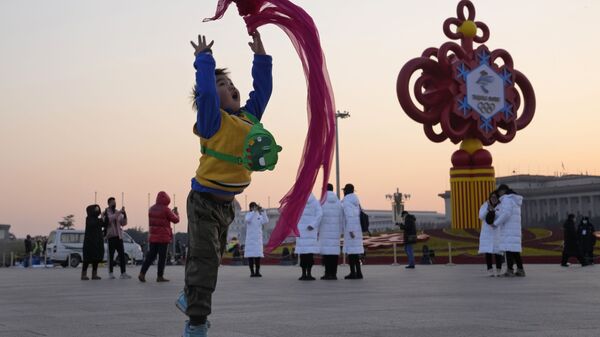 Ребенок играет с красным шарфомна площади Тяньаньмэнь в Пекине - Sputnik Азербайджан