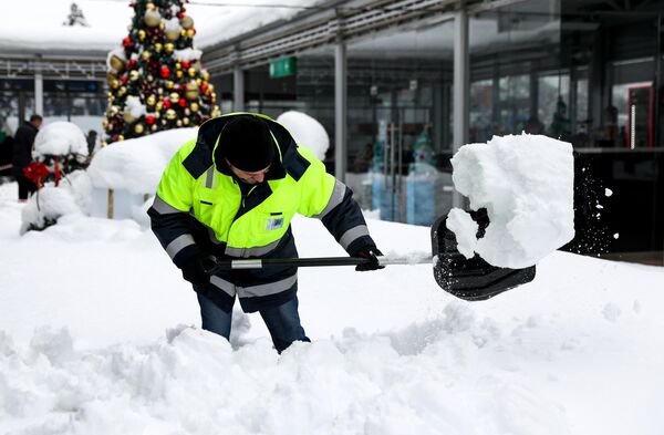 Сотрудник коммунальной службы убирает снег в международном аэропорту Краснодара имени Екатерины II.  - Sputnik Азербайджан