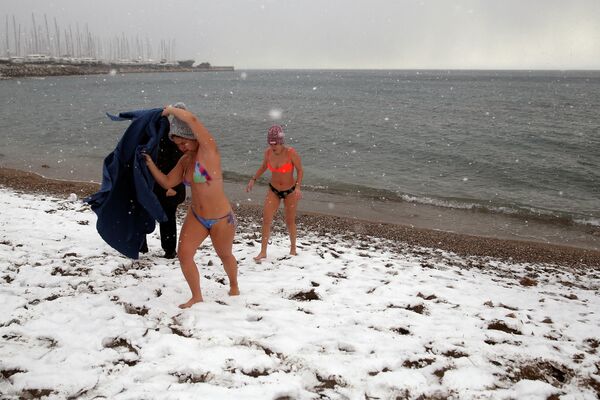 Женщины выходят из моря после купания на заснеженном пляже в Алимос, Греция. - Sputnik Азербайджан