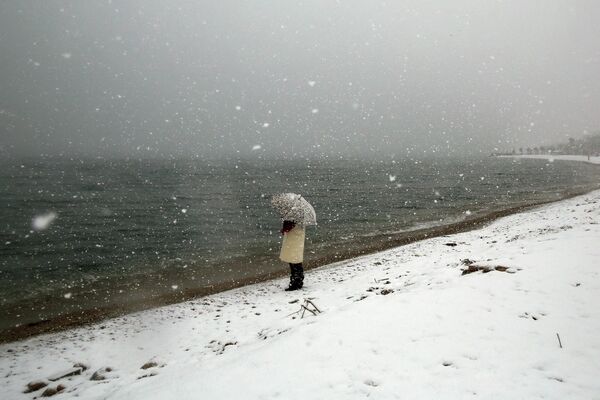 Женщина смотрит на море на заснеженном пляже в Алимос, Греция. - Sputnik Азербайджан