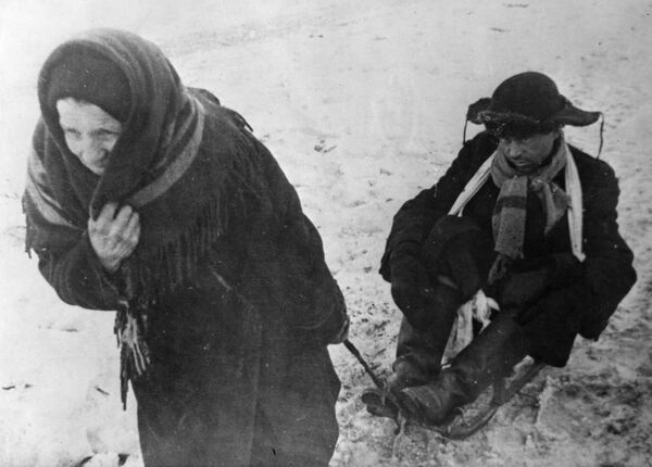 Первая блокадная зима была особенно лютой, морозы достигали 40 градусов. Женщина везет ослабевшего от голода мужа на санках.  - Sputnik Азербайджан
