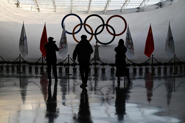 Люди фотографируют олимпийский огонь и кольца в Олимпийской башне в Пекине. - Sputnik Азербайджан