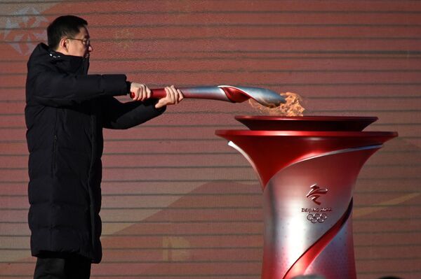 Вице-премьер Госсовета КНР Хань Чжэн передает спортсмену олимпийский факел во время церемонии в Олимпийском лесном парке . - Sputnik Азербайджан