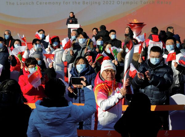 Зрители аплодируют, когда первый факелоносец Луо Чжихуань несет олимпийский огонь. - Sputnik Азербайджан