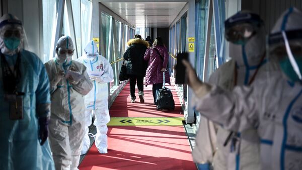 Медицинские сотрудники в защитных костюмах на телескопическом трапе в аэропорту Шоуду в Пекине - Sputnik Азербайджан