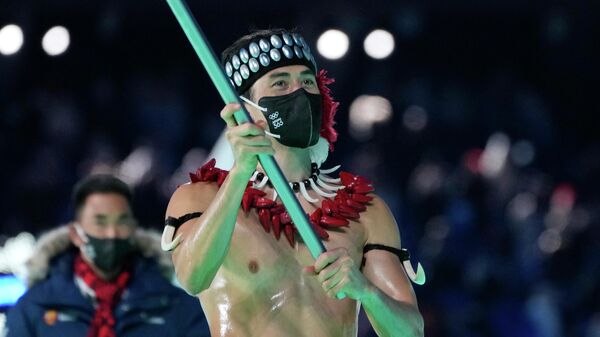 Натан Крамптон из Американского Самоа несет свой национальный флаг во время церемонии открытия Зимних Олимпийских игр 2022 года в Пекине. - Sputnik Азербайджан