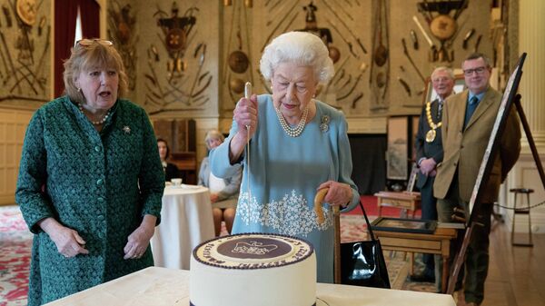 Королева Великобритании Елизавета II разрезает торт в честь начала своего Платинового юбилея во время приема в бальном зале Сандрингемского дома, резиденции королевы в Норфолке, 5 февраля 2022 года. - Sputnik Азербайджан