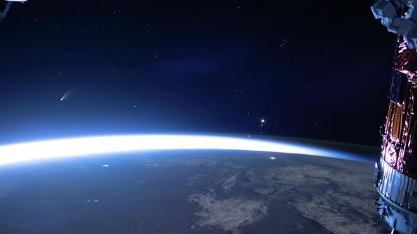 Комета Neowise (слева) видна на восточном горизонте над Землей на изображении, полученном с Международной космической станции, 5 июля 2020 года - Sputnik Азербайджан