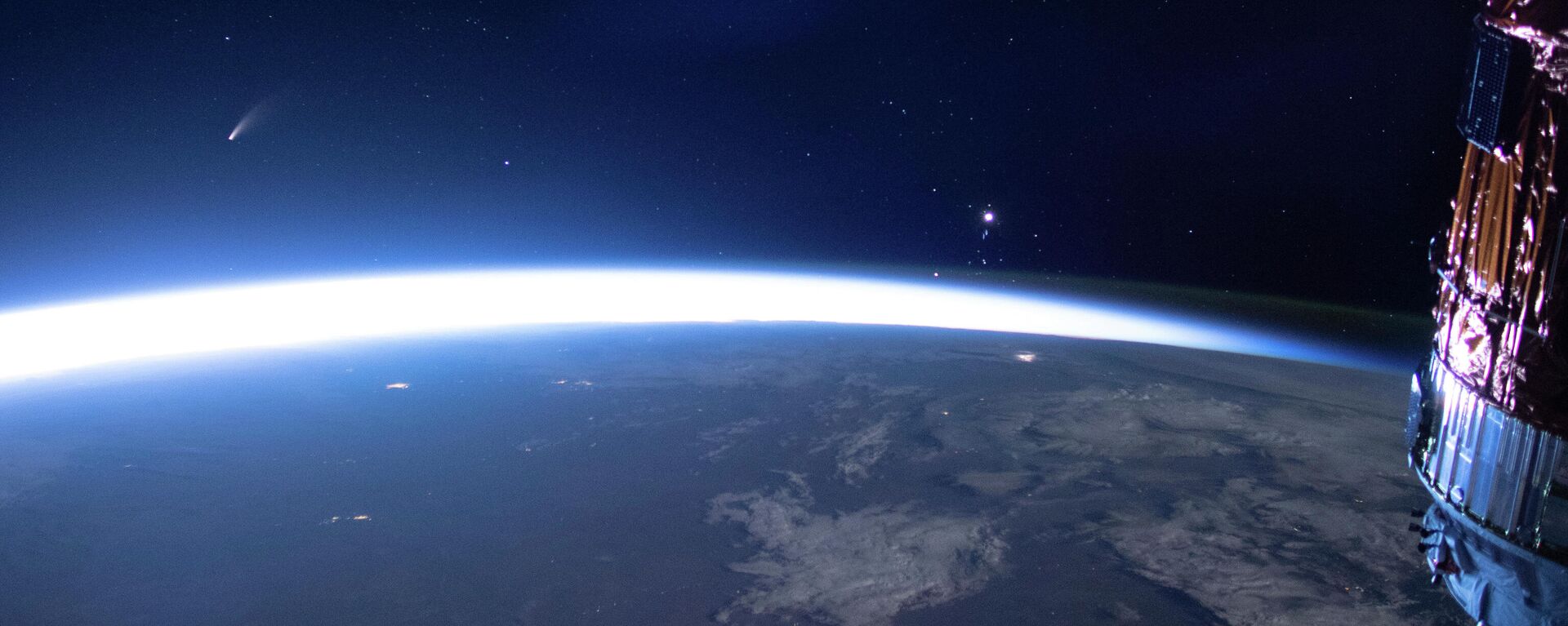 Комета Neowise (слева) видна на восточном горизонте над Землей на изображении, полученном с Международной космической станции, 5 июля 2020 года - Sputnik Азербайджан, 1920, 17.04.2024