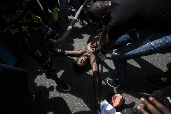 Протестующий имитирует насильственную смерть конголезского иммигранта, убитого ранее на этой неделе в Рио-де-Жанейро, Бразилия - Sputnik Азербайджан