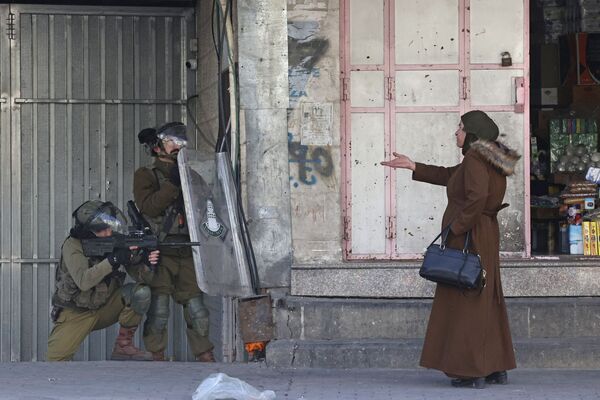 Женщина указывает на израильские силы безопасности в городе Хеврон - Sputnik Азербайджан