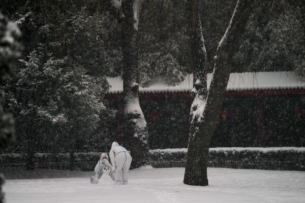 Рабочие в защитных костюмах играют со снегом на зимних Олимпийских играх 2022 в Пекине. - Sputnik Азербайджан