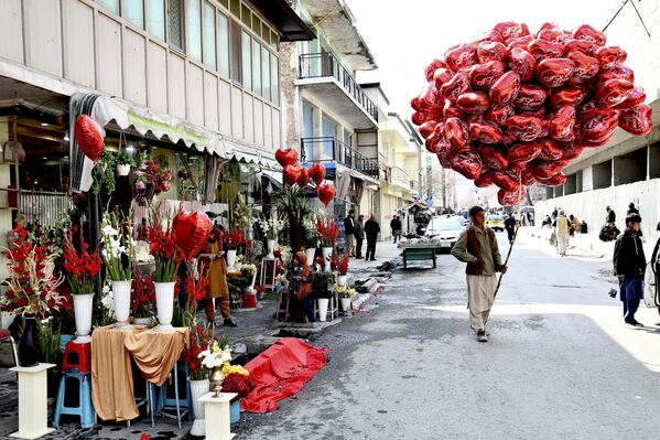 Уличный торговец несет воздушные шары в форме сердца, ожидая покупателей в День святого Валентина в Кабуле. - Sputnik Азербайджан