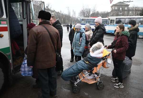 İnsanlar uşaqları ilə birgə Qorlovkadan Rusiya ərazisinə təxliyə zamanı avtobusun yanında dayanıblar. - Sputnik Azərbaycan