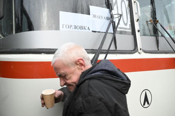 Yaşlı kişi Qorlovkadan Rusiya ərazisinə təxliyə zamanı avtobusun qarşısında dayanıb. - Sputnik Azərbaycan