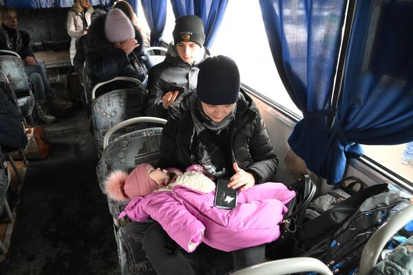 Qadınlar uşaqları ilə birgə Qorlovkadan Rusiya ərazisinə təxliyə zamanı avtobusda oturublar. - Sputnik Azərbaycan