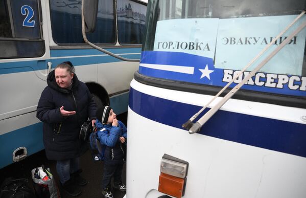 Женщина с ребенком стоит возле автобуса  во время эвакуации из Горловки на территорию России.  - Sputnik Азербайджан