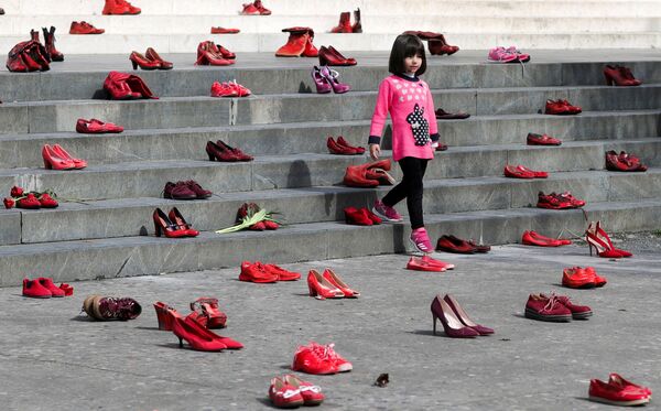 Девочка посреди инсталляции в честь 8-го марта, выполненной из красных туфель, как символ осуждения насилия в отношении женщин, в Тиране, Албания. - Sputnik Азербайджан