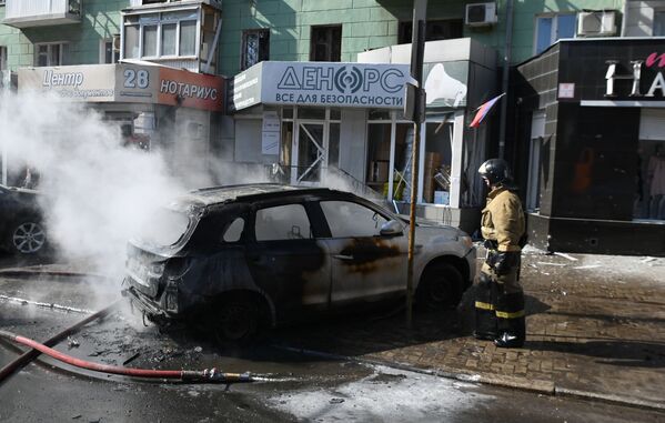 Сотрудник пожарной охраны у разрушенной машины в результате взрыва в центре Донецка.  - Sputnik Азербайджан