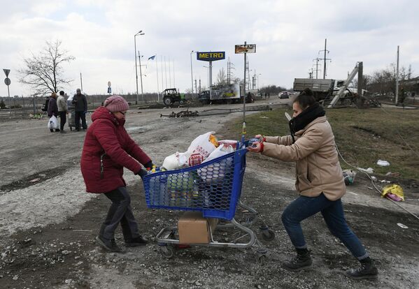 Местные жительницы тянут тележку с продуктами возле магазина Metro в Мариуполе - Sputnik Азербайджан