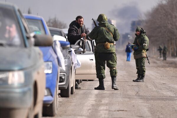 Один из военнослужащих  дает прикурить мужчине стоящему в пробке на выезде из Мариуполя. - Sputnik Азербайджан