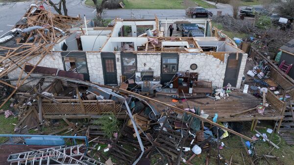 Женщина идет через гараж разрушенного дома после торнадо в Раунд-Рок, штат Техас. - Sputnik Азербайджан
