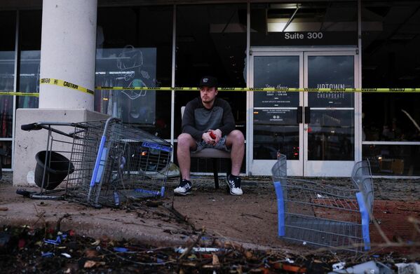 Мужчина сидит возле поврежденного в результате торнадо магазина, Раунд-Рок, штат Техас. - Sputnik Азербайджан