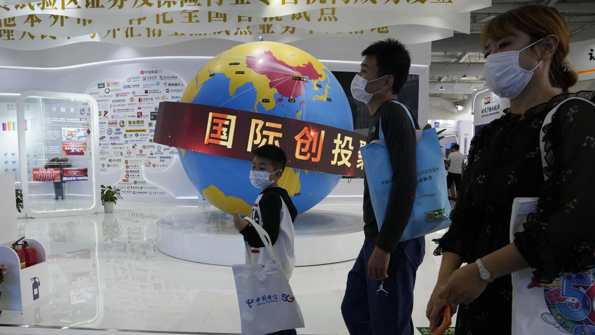 Посетители Китайской международной выставки проходят мимо глобуса с изображением зоны торгового оборота Китая  - Sputnik Азербайджан, 1920, 01.04.2022