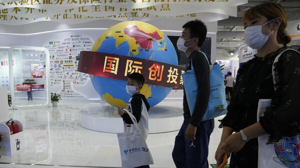 Посетители Китайской международной выставки проходят мимо глобуса с изображением зоны торгового оборота Китая  - Sputnik Азербайджан