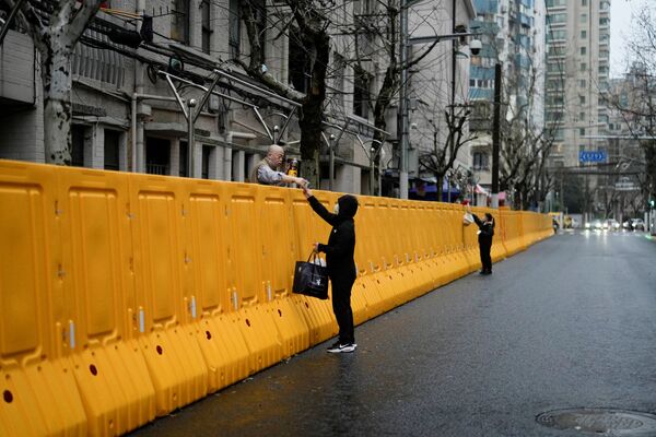 Люди передают еду жителям через барьеры закрытого района на фоне пандемии COVID-19 в Шанхае, Китай, 25 марта 2022 года. - Sputnik Азербайджан