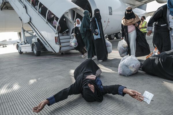Эфиопская женщина, репатриированная из Саудовской Аравии, высаживается из самолета в аэропорту Боле в Аддис-Абебе. - Sputnik Азербайджан